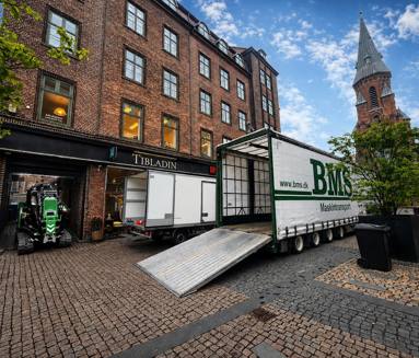 Minikran transporteres gennem en smal port til baggård i Aarhus.