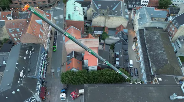 Luftfoto af mobilkranens bom, der rækker hen over Magasins bygning i Odense.