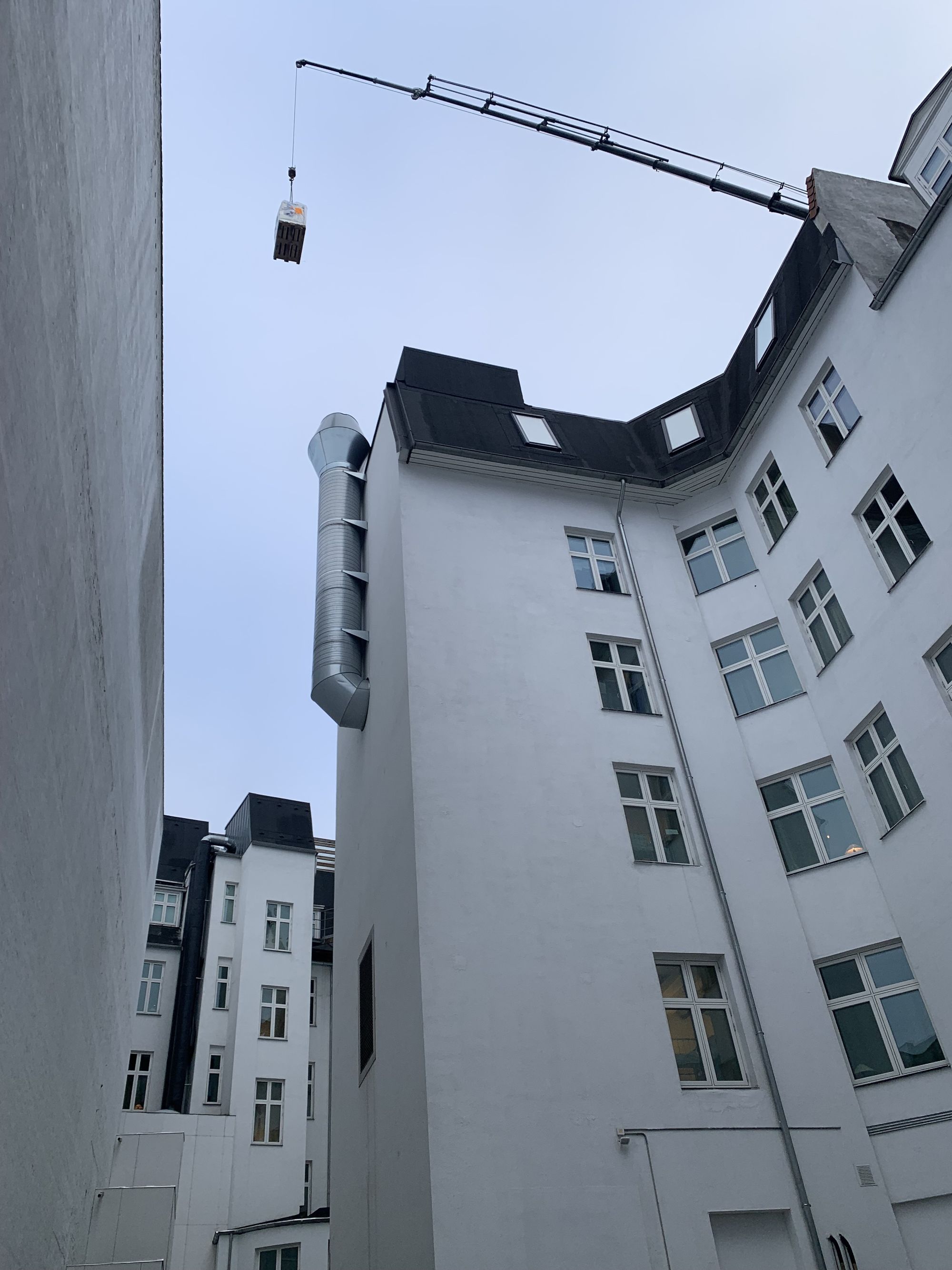 Kran hæver gods forbi tag og ventilationsrør på vej til koblingsanlægget