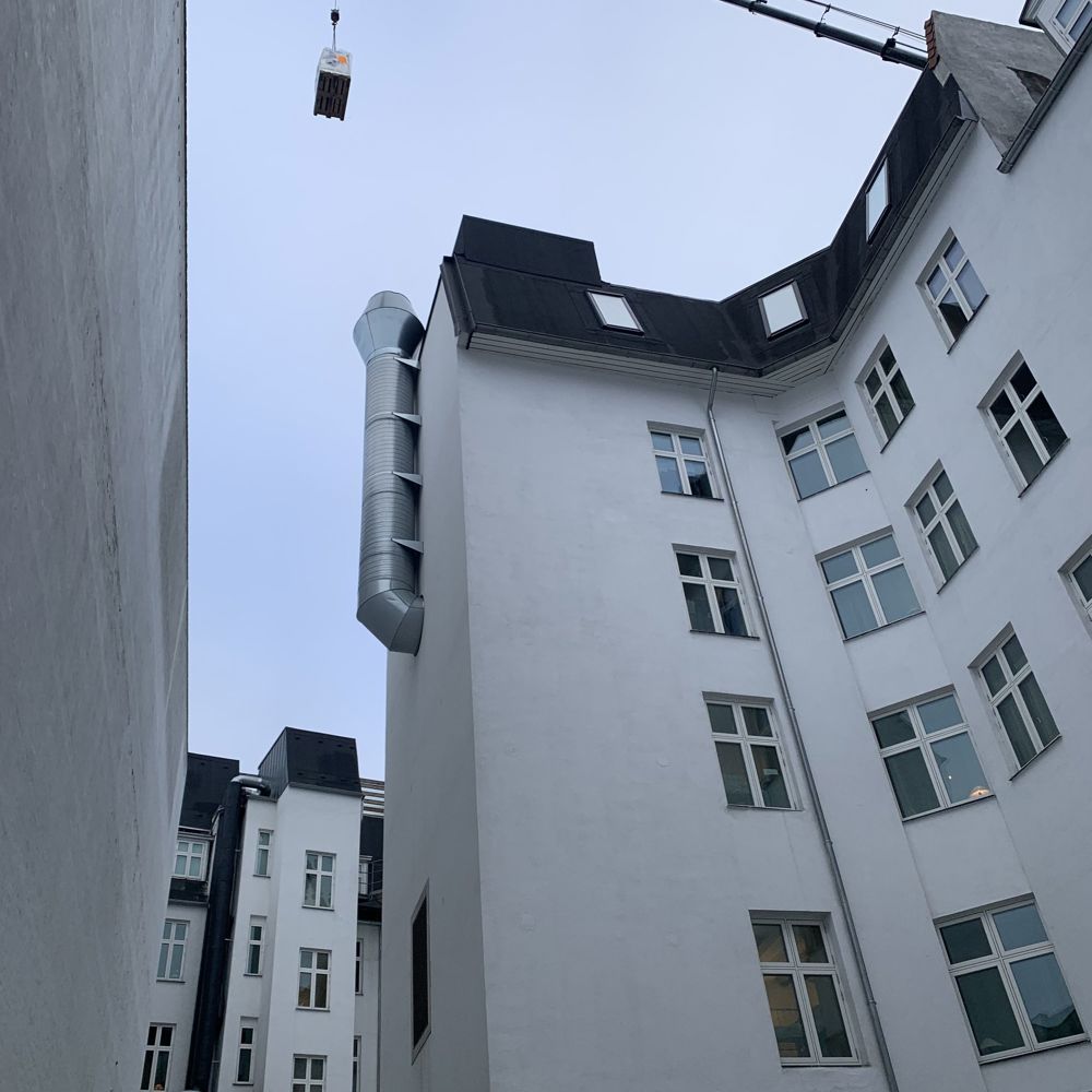 Kran hæver gods forbi tag og ventilationsrør på vej til koblingsanlægget