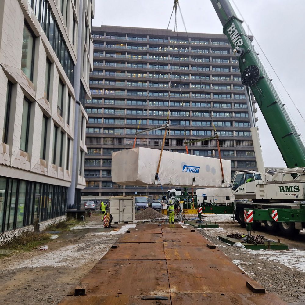 Mobilkran hejser stort trykkammer op mellem højhuse ved Rigshospitalet