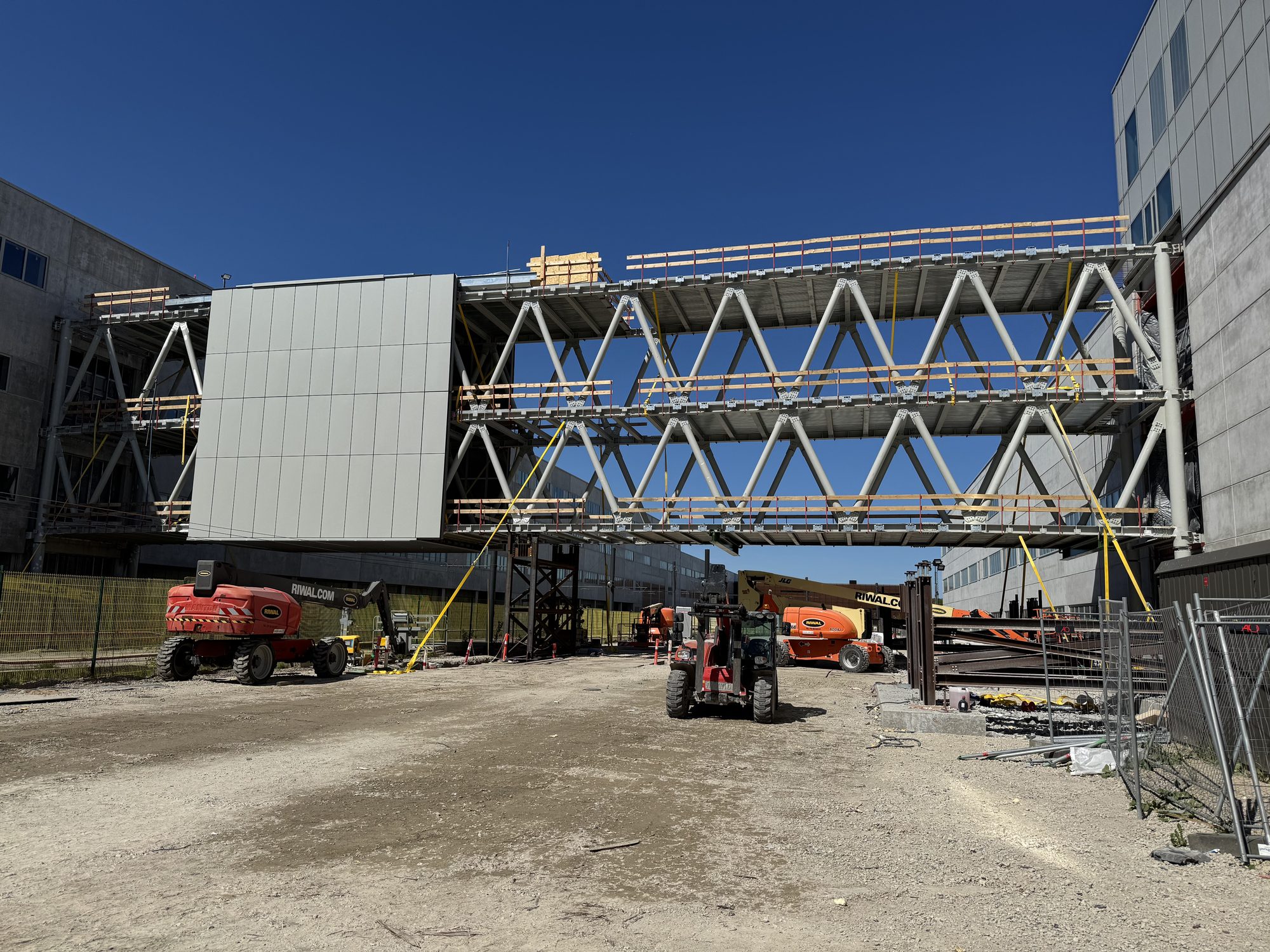 skybridge under opførelse mellem to bygninger, med lifte parkeret nedenunder
