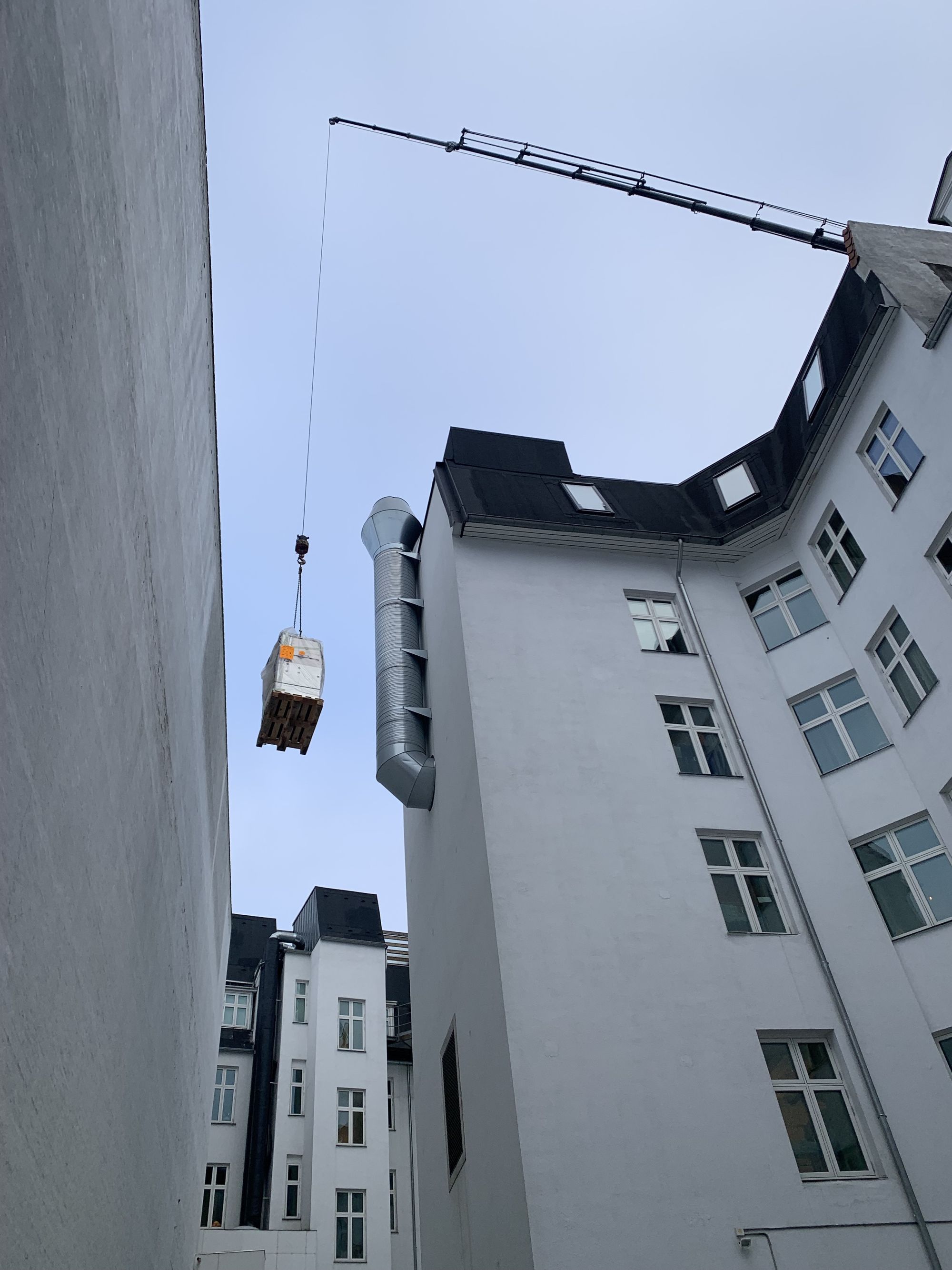 Kran hæver gods forbi tag og ventilationsrør på vej til koblingsanlægget