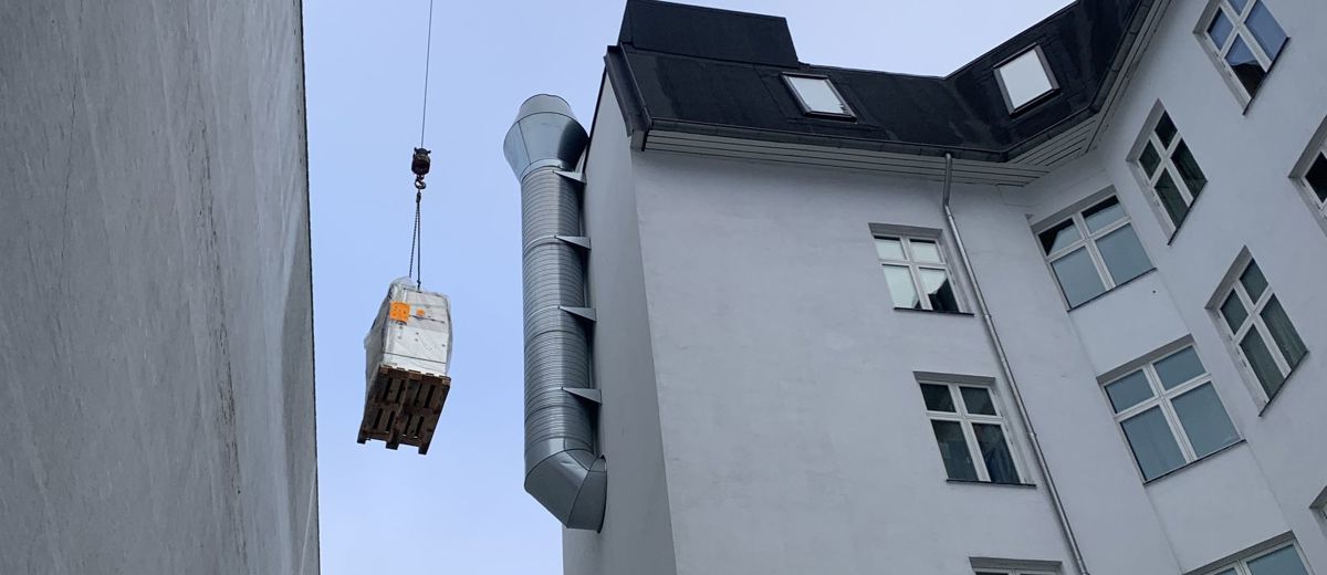Kran hæver gods forbi tag og ventilationsrør på vej til koblingsanlægget
