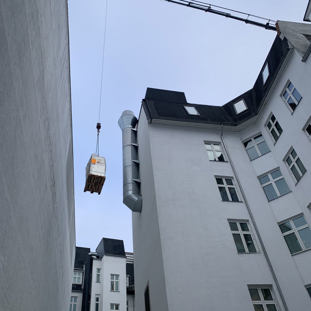 Kran hæver gods forbi tag og ventilationsrør på vej til koblingsanlægget