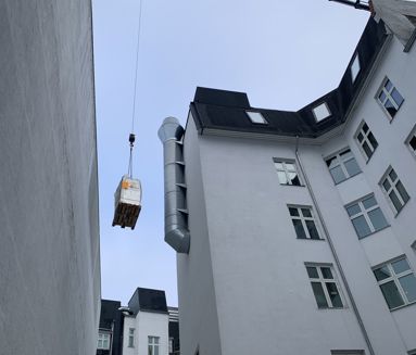 Kran hæver gods forbi tag og ventilationsrør på vej til koblingsanlægget