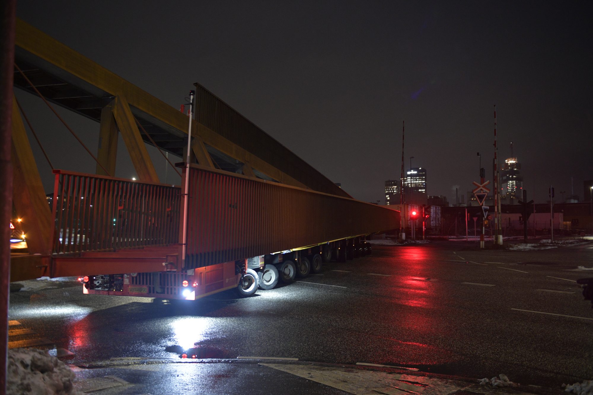 Selvkørende modultransporter (SPMT) kører en stor stål-gangbro gennem Aarhus Havn om natten i sne