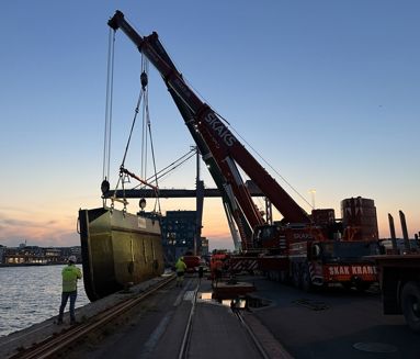 Flere mobilkraner tandemløfter den historiske dokport ved solnedgang i København