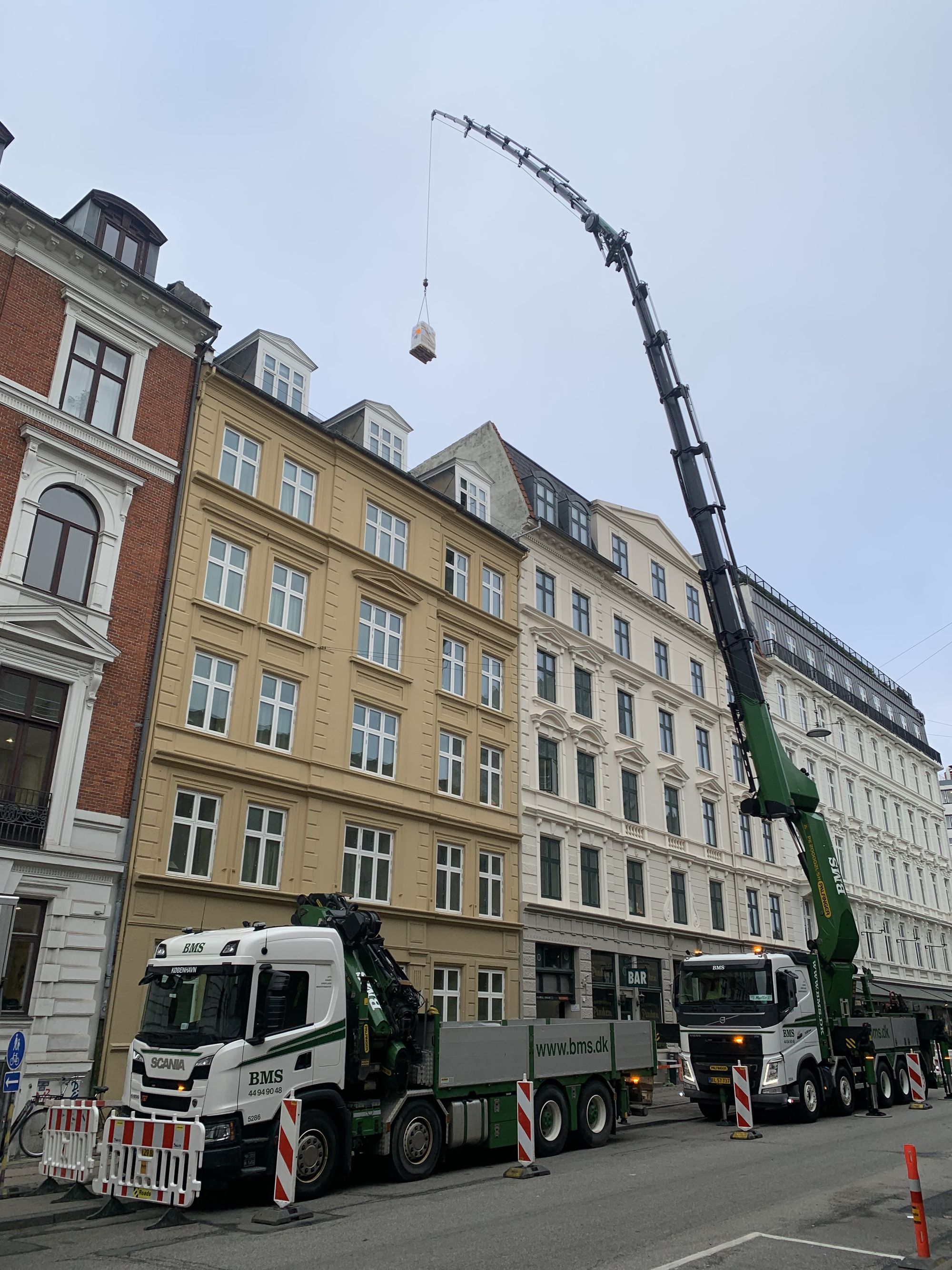 Lastbilkran hejser udstyr op over ejendomme i det centrale København